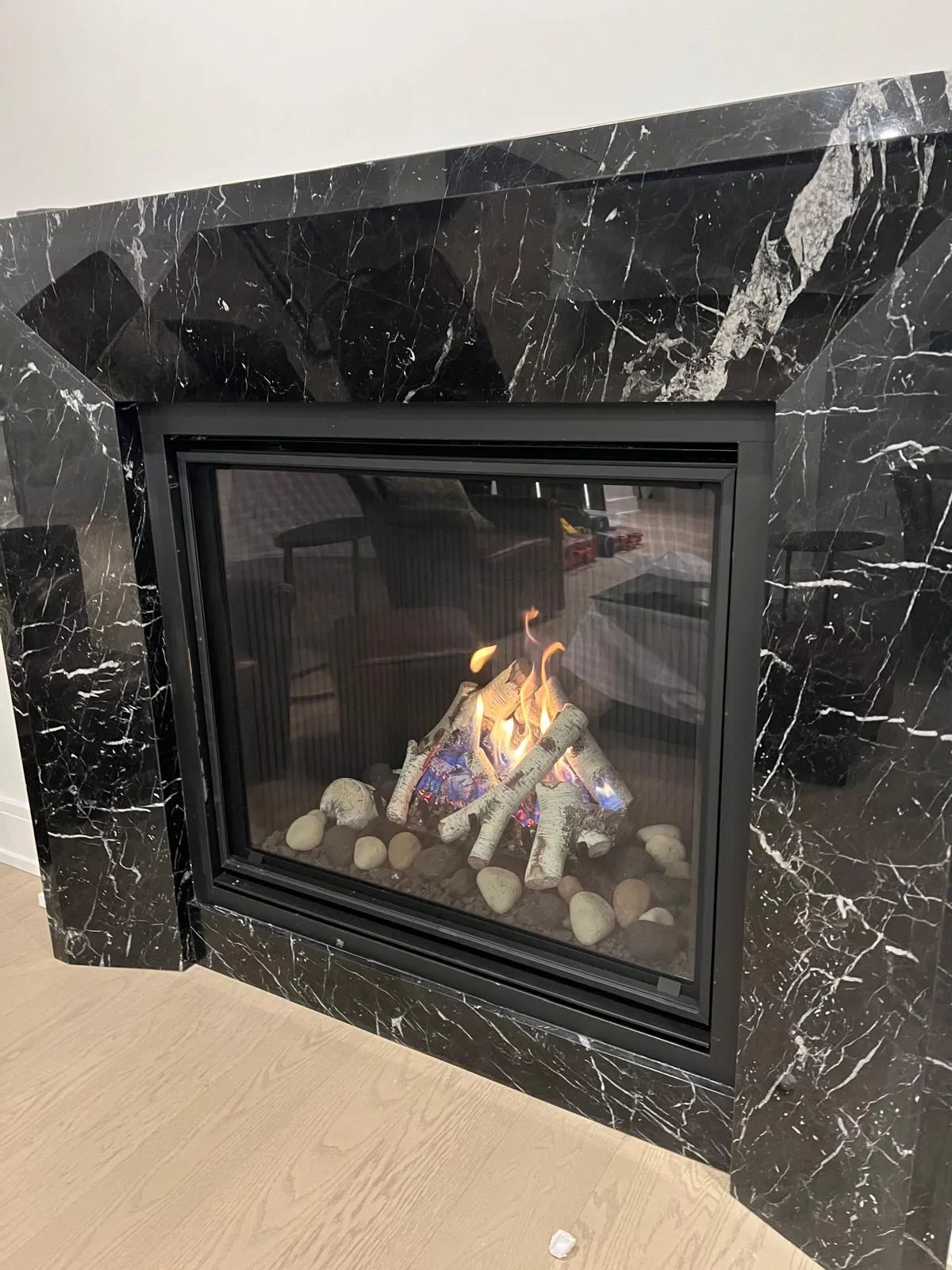 Linear gas fireplace in a polished black marble wall