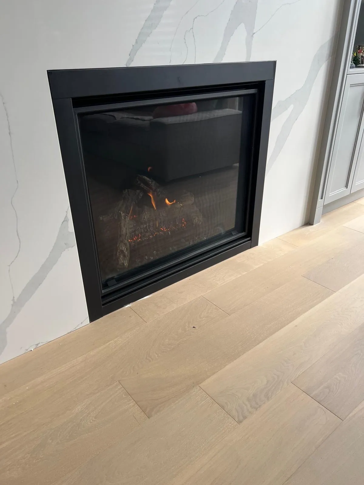 Modern linear gas fireplace with marble surround in a GTA living room